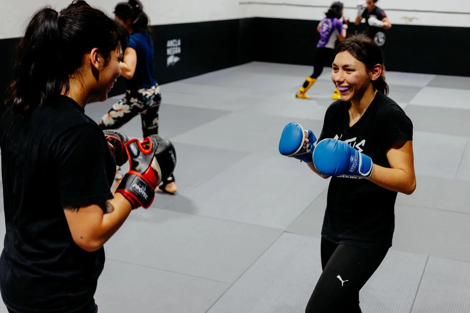Two women engaged in martial arts training at an indoor gym in Buenos Aires.